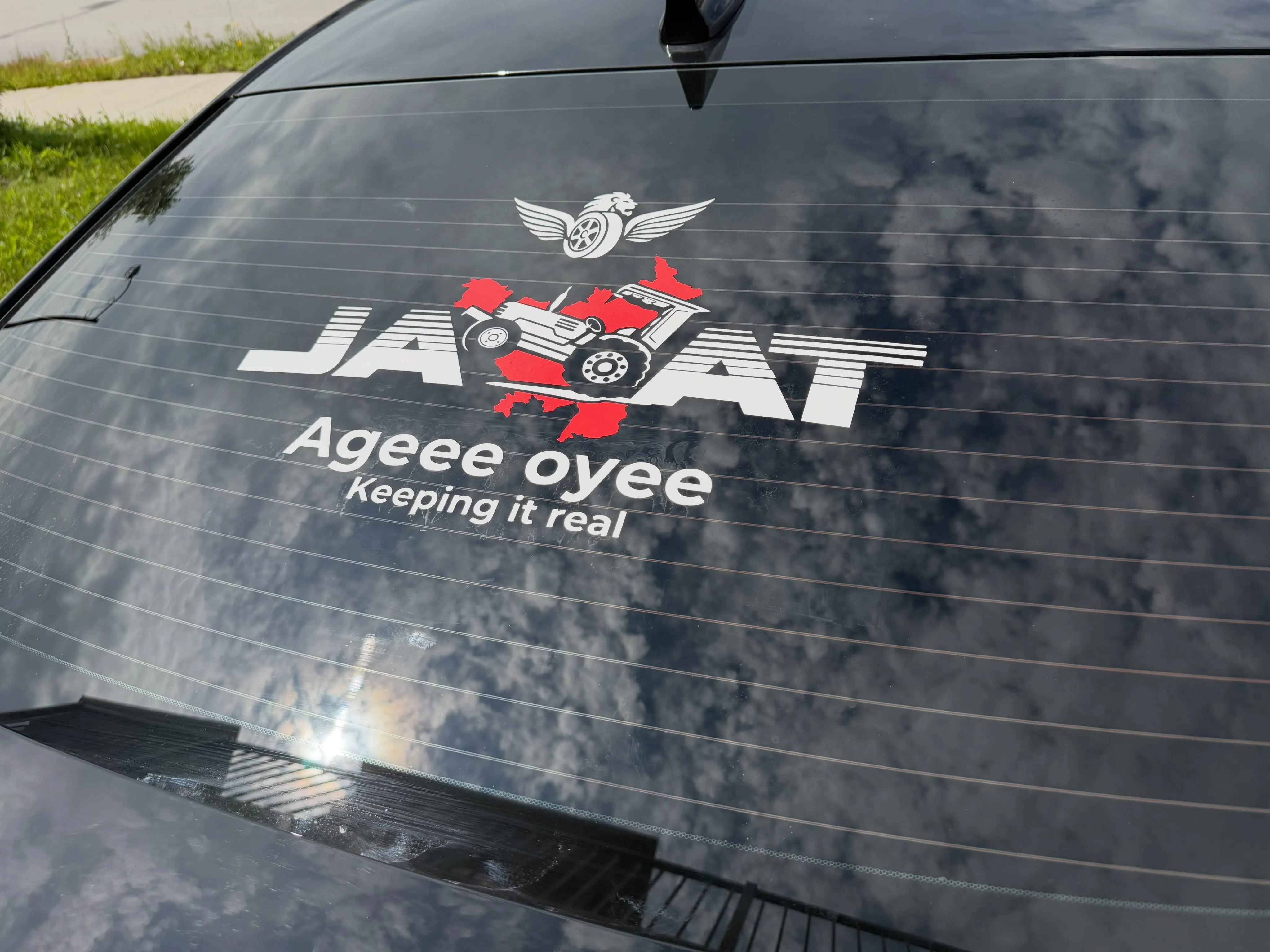 JATT logo with tractor illustration and tagline lettering applied to the rear window of a dark sedan