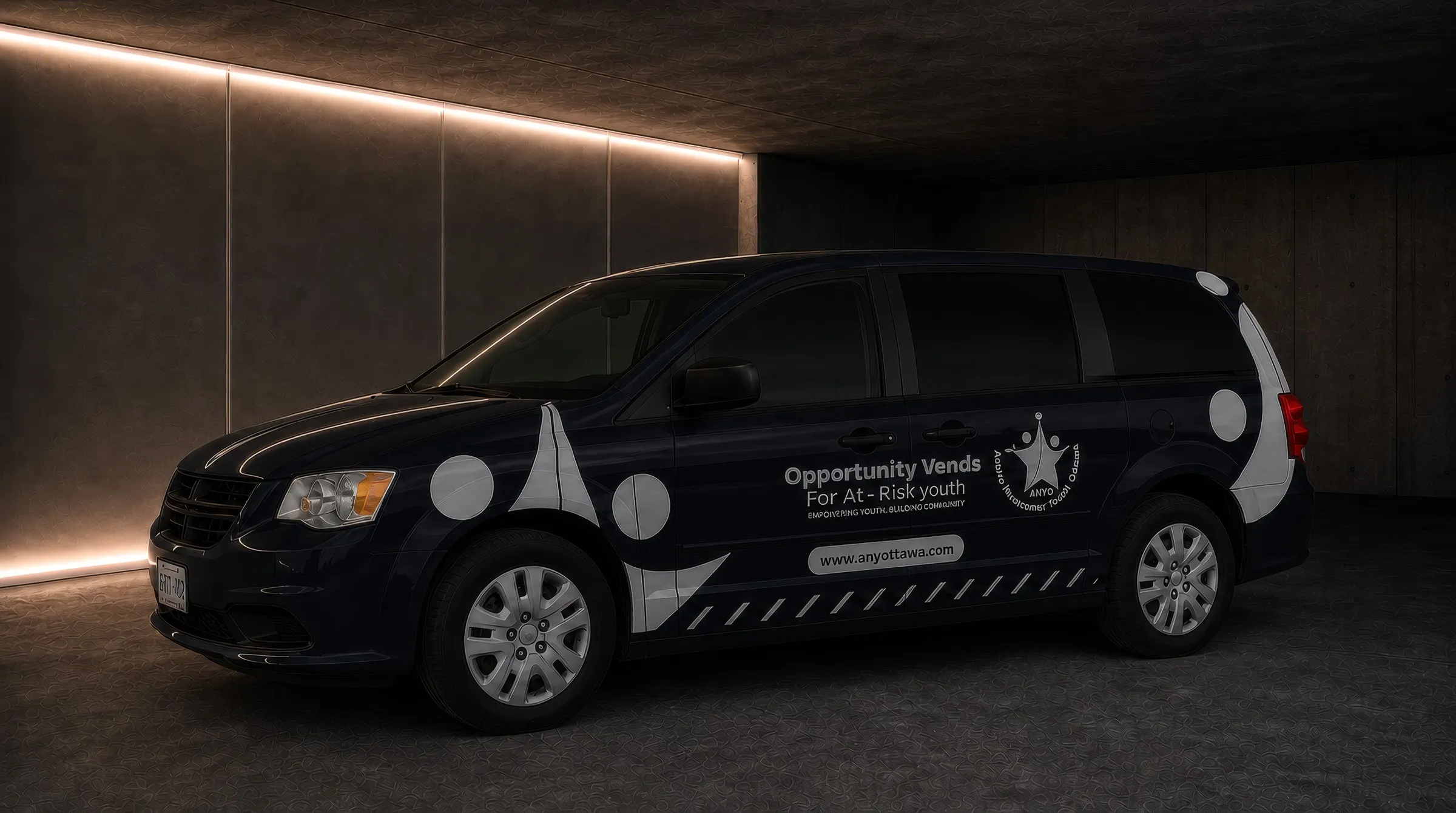 Navy minivan with white cut vinyl graphics and a youth programme wordmark along the sliding door