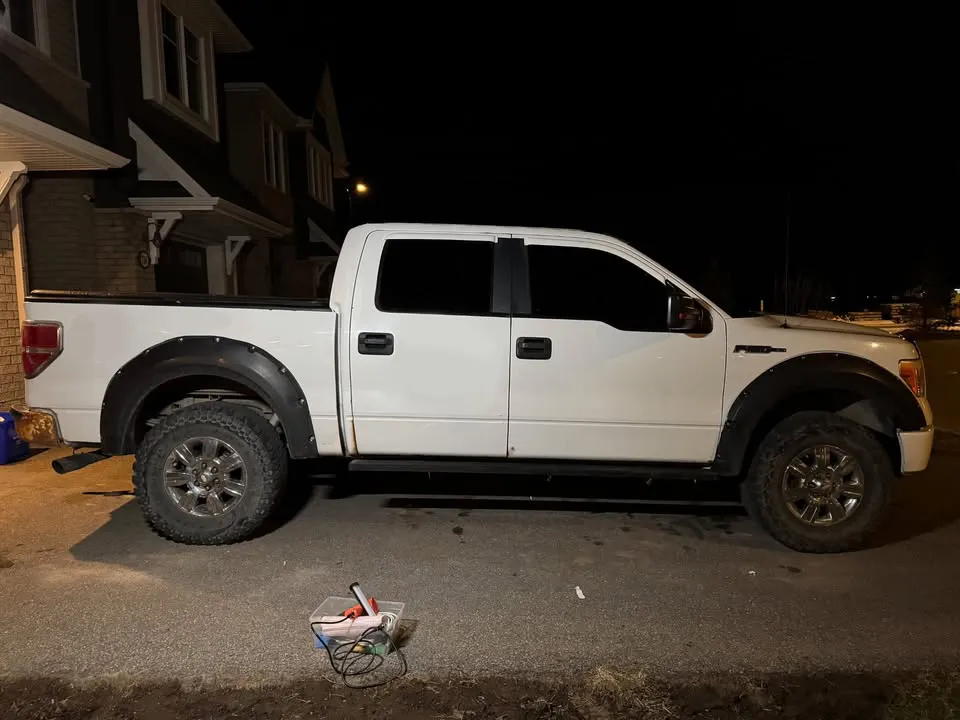 White crew cab pickup with bare doors and bed side before lettering