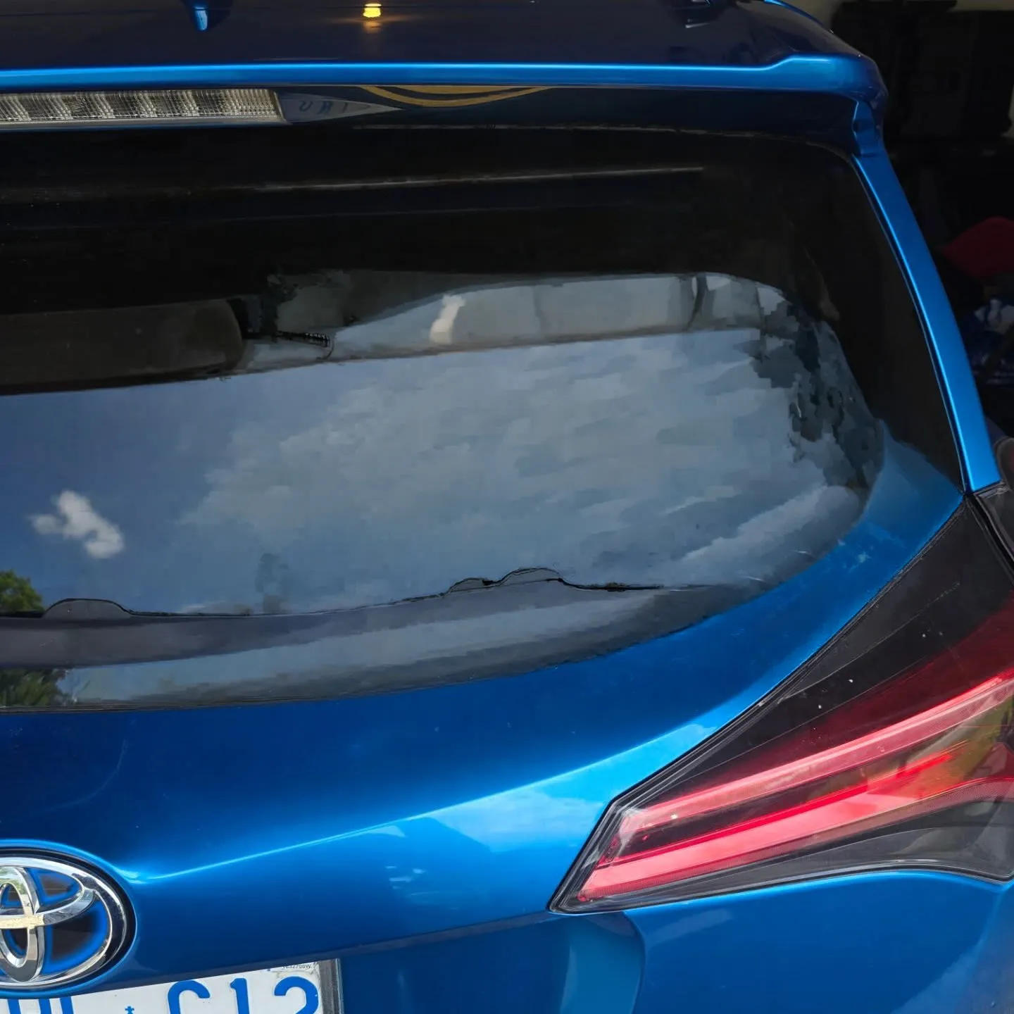 Bare rear window on a blue hatchback before the decal was applied
